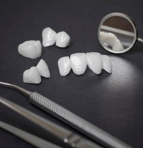 Several dental crowns laying on table next to dental instruments