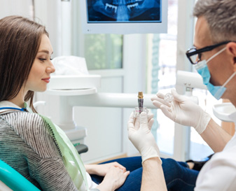 Dentist showing large model implant to patient